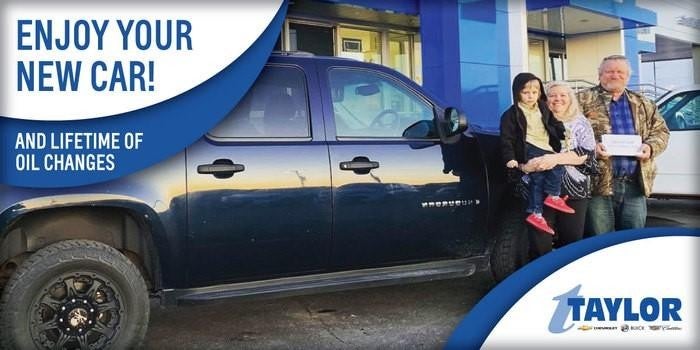 A joyful family posing together in front of their car