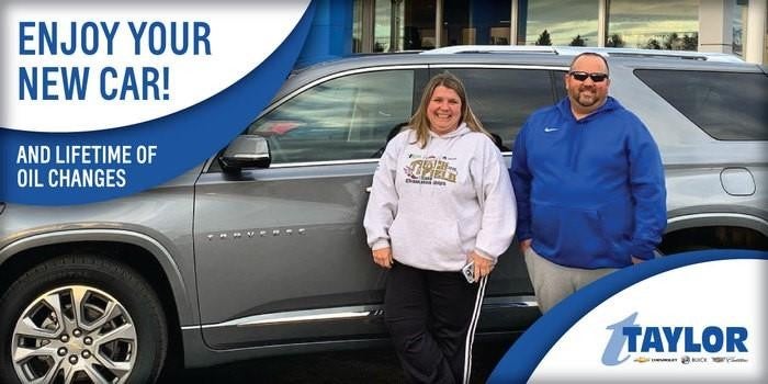 Two people smiling in front of their car, capturing a joyful and carefree moment.